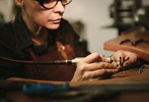 conservation-image02 Lady wearing glasses using fine metal working tools to restore some intricate cupboard handles.