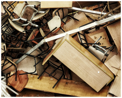 Wooden and upholstered fast furniture lying discarded in a pile.