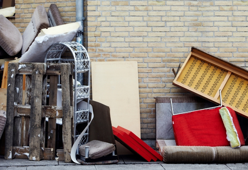 fast-furniture01 Pile of fast furniture lying discarded in the street against a brick wall.
