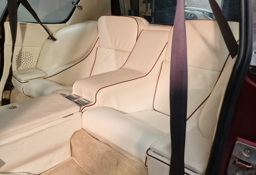 The rear seats of a Lotus car interior in cream leather with a contrast red piped trim.