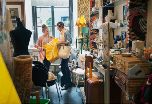 Two women shopping in a vintage shop, full of vintage homeware and furniture