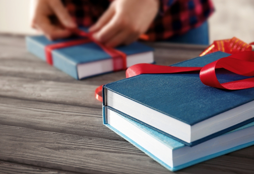 Collection of hard-backed vintage books being wrapped with ribbon