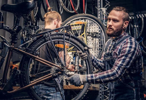 man-in-workshop-repairing-bike Man in his workshop repairing and servicing a bike