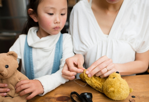 woman-and-young-girl-fixing-teddy-bear Woman and young girl fixing a teddy bear at home