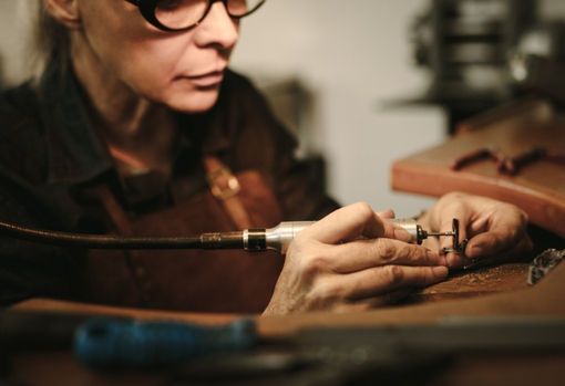 A female jeweller in her workshop repairing a ring