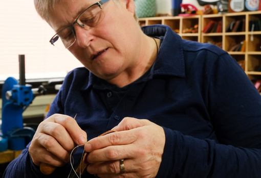 A female leather worker in her workshop repairing a bag