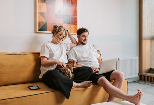 Man and woman sat on yellow sofa together in their living room
