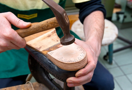 A cobbler fixing a new sole to a shoe